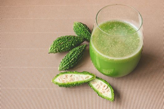 Herbal juice with bitter melon or bitter gourd on wooden background.