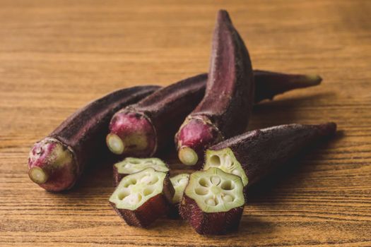 Fresh Red okra on wooden background.