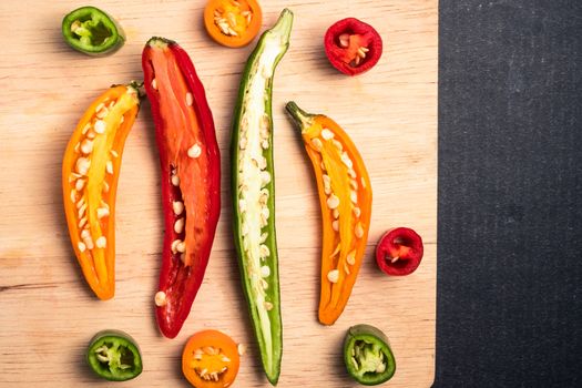Colorful mix of chili pappers on wooden tray over black background.