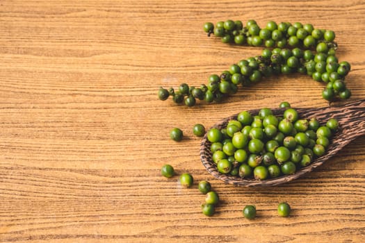 Green peppercorns on wooden background. Free space for text