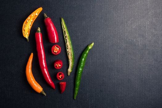 Colorful mix of chili pappers on black background. Free space for text