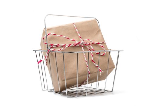 Gift package wrapped in brown paper in basket on white background.