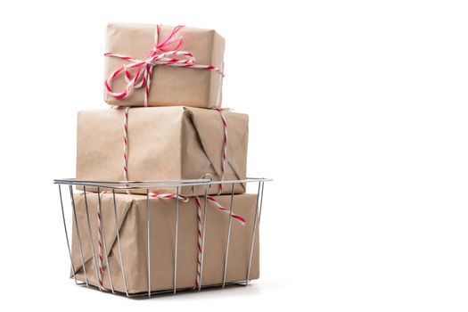 Gift packages wrapped in brown paper in basket on white background.
