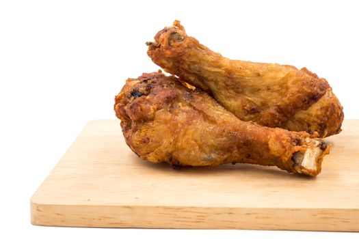 Fried chicken legs on wooden tray over a white background.