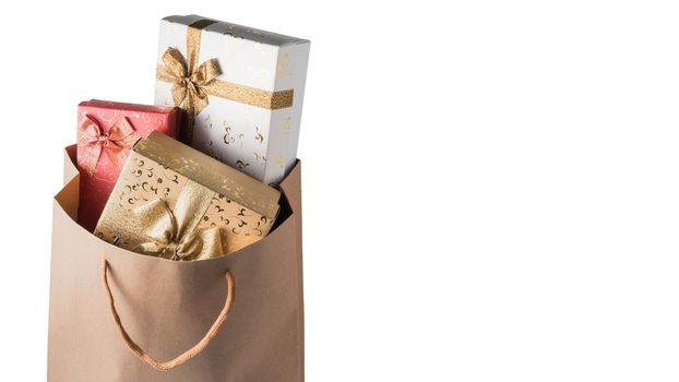 Gift boxes in brown paper bag on white background. Free space for text