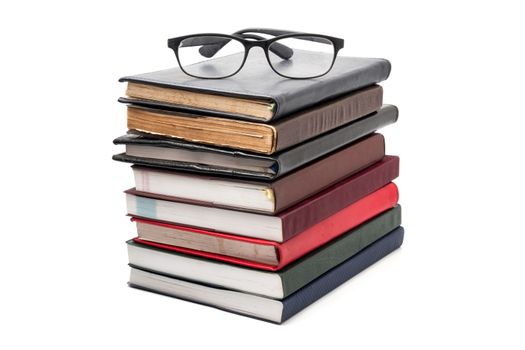 A stack of books with eyeglasses on a white background.