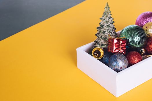 Christmas decorations in white box on colorful background.