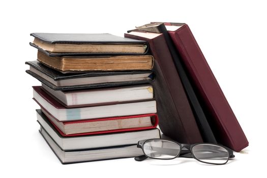 A stack of books with eyeglasses on a white background.