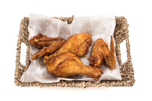 Fried chicken legs and wings in basket on a white background.