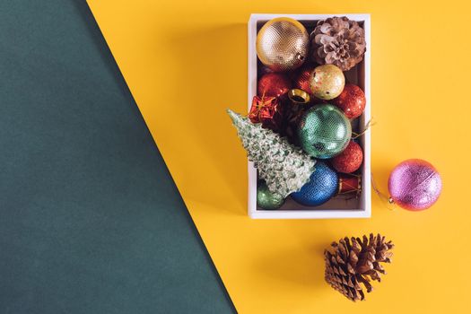 Christmas decorations in white box on colorful background.