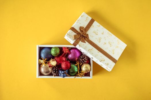Christmas decorations in gift box on a yellow background.