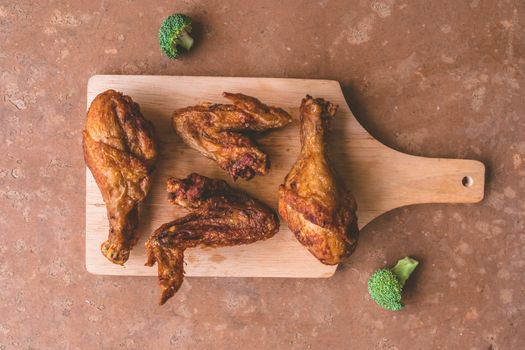 Top view of Fried chicken legs and wings on wooden tray.