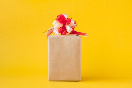 Gift packages wrapped in brown paper with bow on yellow background.