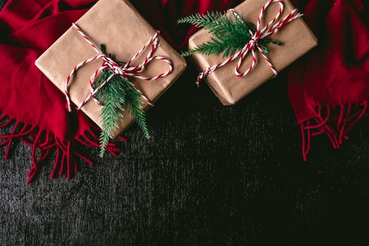 Top view of Gift packages wrapped in brown paper and red scarf on black background. Free space for text