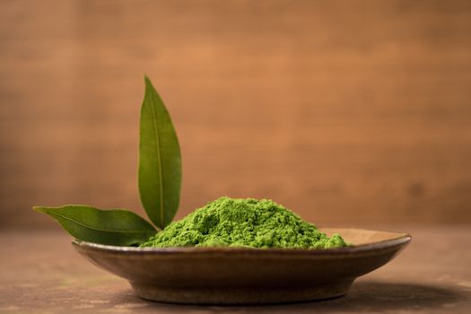 Close up of green tea powder with leaf  in ceramic dish on the table.