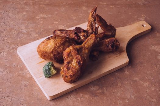 Fried chicken legs and wings on wooden tray.