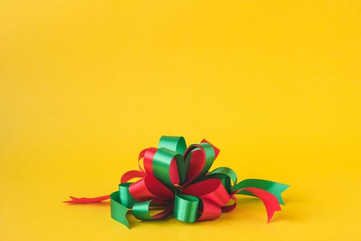 Colorful gift bow on yellow background.