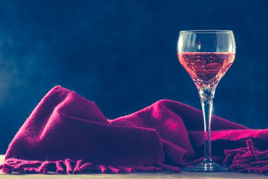 Glass of wine with red scarf on the table, black background, Free space for text, Vintage tone