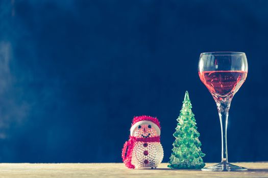 Glass of wine with Christmas decorations on the wooden table, black background, free space for text, vintage tone
