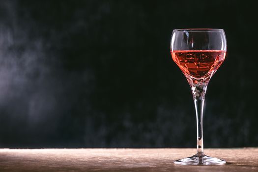 Glass of wine on the wooden table, black background. free space for text.