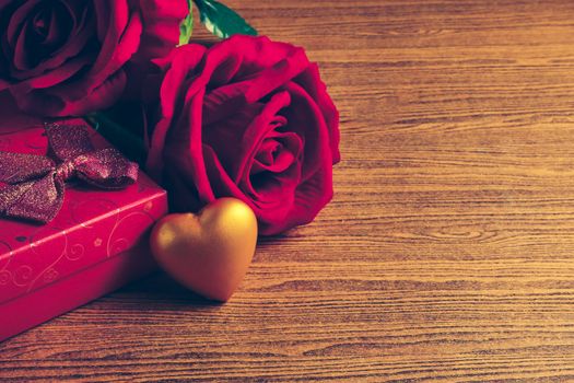 Gold heart with gift box and red rose on wooden background. Concept of Valentine Day.