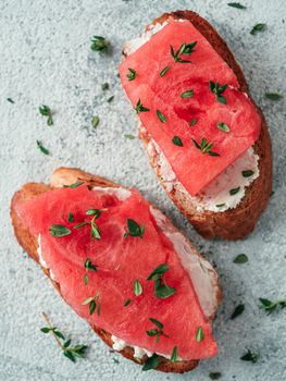 Toasts with soft cheese and watermelon.Salty cheese,sweet watermelon and spicy thyme on crispy grilled bread slices.Idea and recipe for unusual healthy breakfast,summer snack or lunch.Top view flatlay