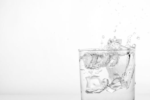 Splashing of water with ice in glass