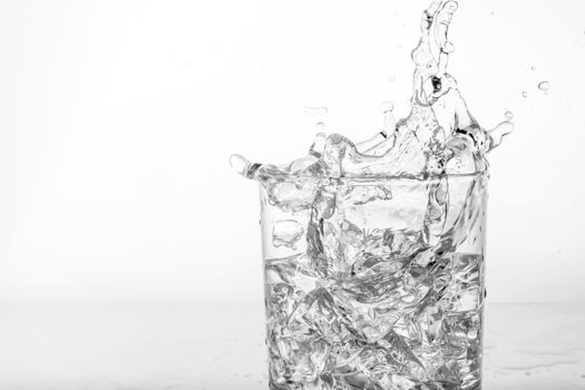 Splashing of water with ice in glass