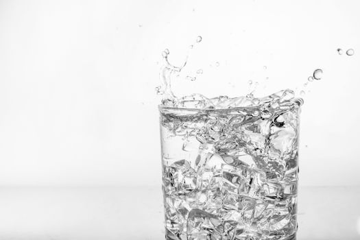 Splashing of water with ice in glass