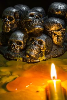 skulls with candle burning on wooden background in the darkness