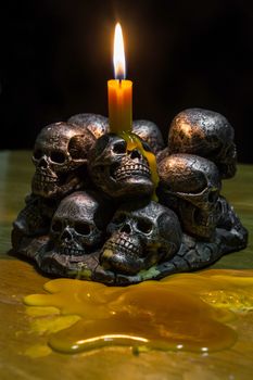 skulls with candle burning on wooden background in the darkness