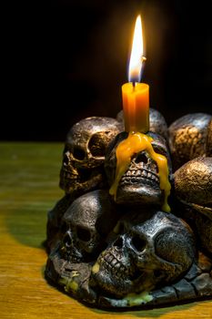 skulls with candle burning on wooden background in the darkness