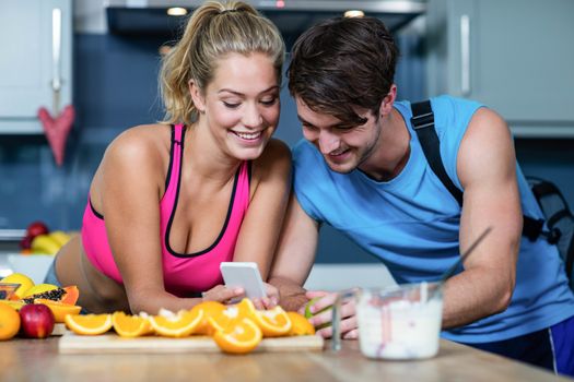 Healthy couple looking at smartphone in the kitchen