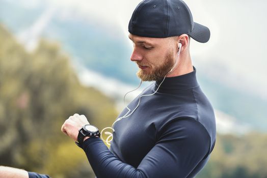 Close-up Shot Bearded Sportive Man After Workout Session Checks Fitness Results. Adult Guy Wearing Sport Tracker Wristband.