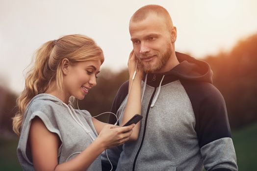 Caucasian sportive couple dating on after training, listening to music, having fun together. Sports and Outdoor Activities, Technology and People Relations Concept