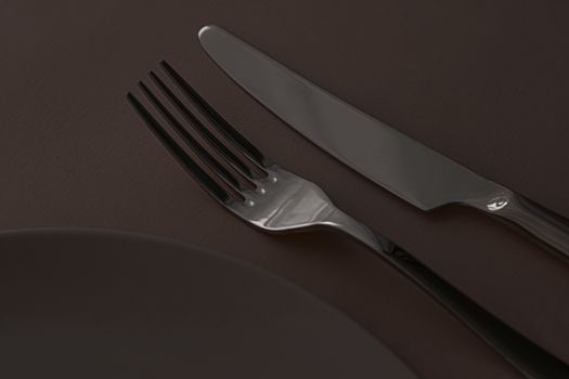 Empty plate and cutlery as mockup set on dark brown background, top tableware for chef table decor and menu branding design