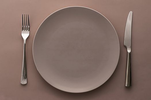 Empty plate and cutlery as mockup set on brown background, top tableware for chef table decor and menu branding design