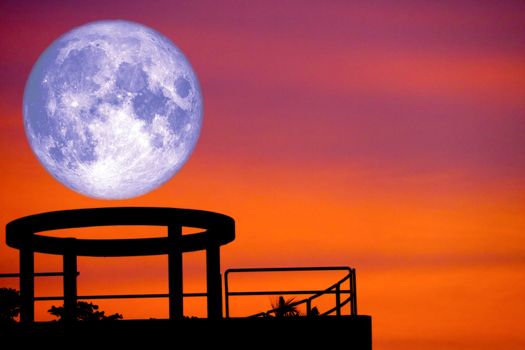 blue moon back over silhouette cycle on roof of building and sunset sky, Elements of this image furnished by NASA