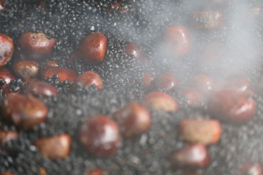 Hot roasted chestnuts on the stove and good smell of smoke