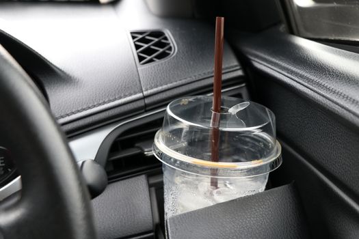 Coffee cups placed in the cup holder next to the car steering wheel.