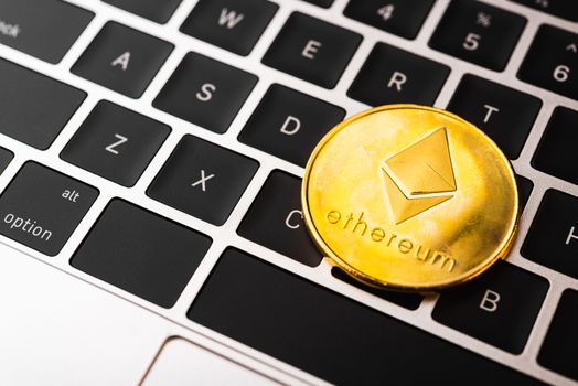 Golden ether coins or Ethereum network exchange on keyboard of laptop computer, electronic money world, blockchain and money cryptocurrency (crypto currency) concept