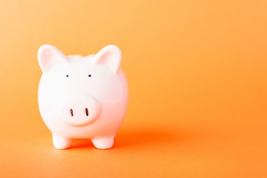 Front small white fat piggy bank, studio shot isolated on orange background and copy space for use, Finance, deposit saving money concept