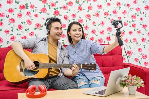 Asian Vlogger of married couple playing the music and taking video and stream live to attendee via mobile phone by social media channel, lovers and valentine, vlog and influencer freelance concept