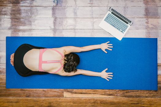 Top view Asian woman practicing yoga from home with laptop when Covid19 outbreak, healthy or Meditation Exercise, workout at home, coronavirus pandemic and quarantine, sports and healthcare in concept
