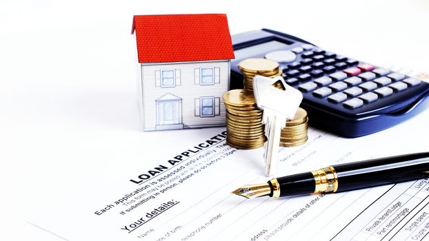 Fountain pen and key and calculator and paper house and coins stack on Laon Application form for Mortgage loans concept