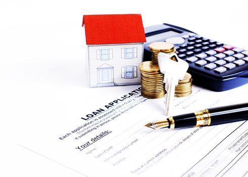 Mortgage loans concept with Fountain pen and key and calculator and paper house and coins stack on Laon Application form