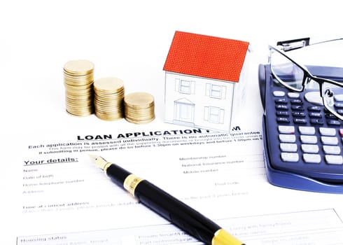 Loans application form and fountain pen and paper house and coins stack and eyeglasses on calculator