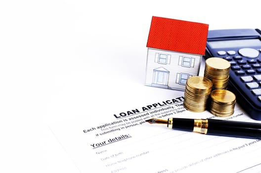 Loan application form and fountain pen and calculator and coins stack and paper house