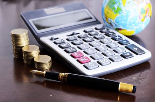 Fountain pen and calculator money coins stack and earth for Business concept