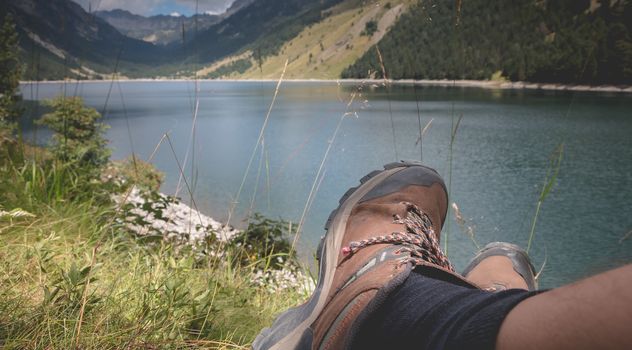 hiker taking a break sitting near the lake of Oule in valley of Aure in Haute-Bigorre in the department of Hautes-Pyrénées in France